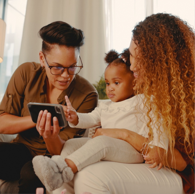 two woman with their child looking at a video on a smartphone